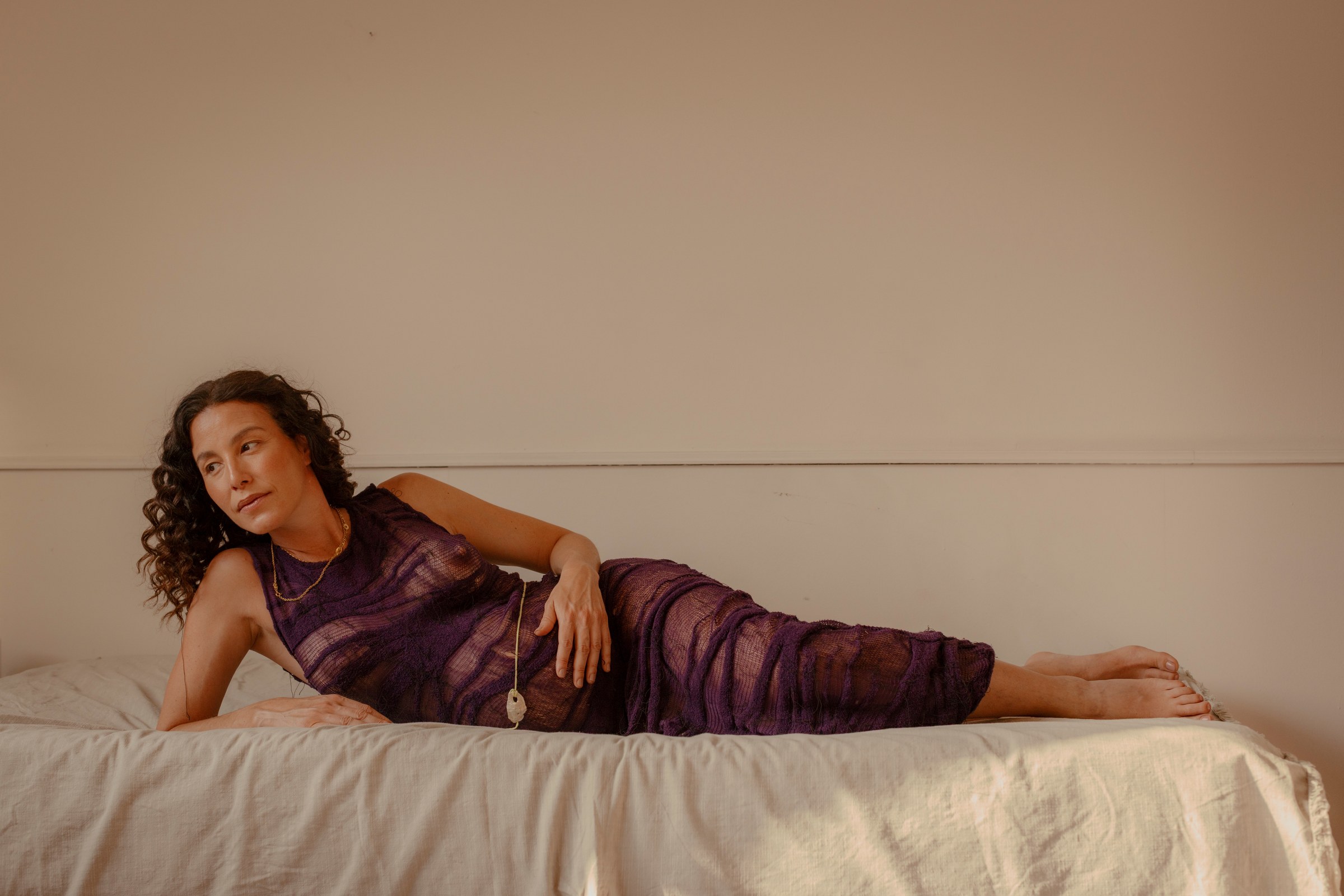 Woman reclining in a purple dress across a bed