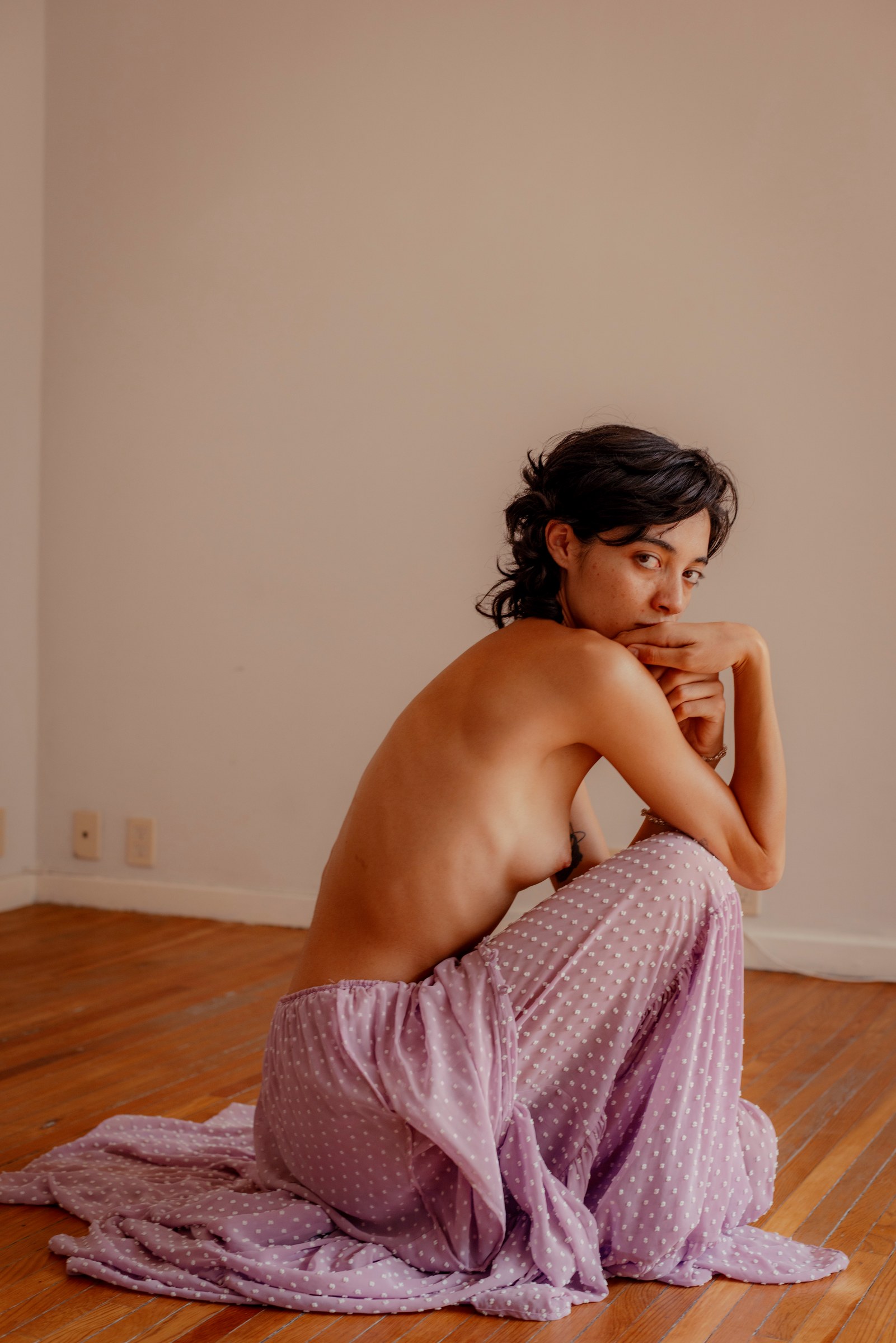 Woman seated on the floor wrapped in violet fabric