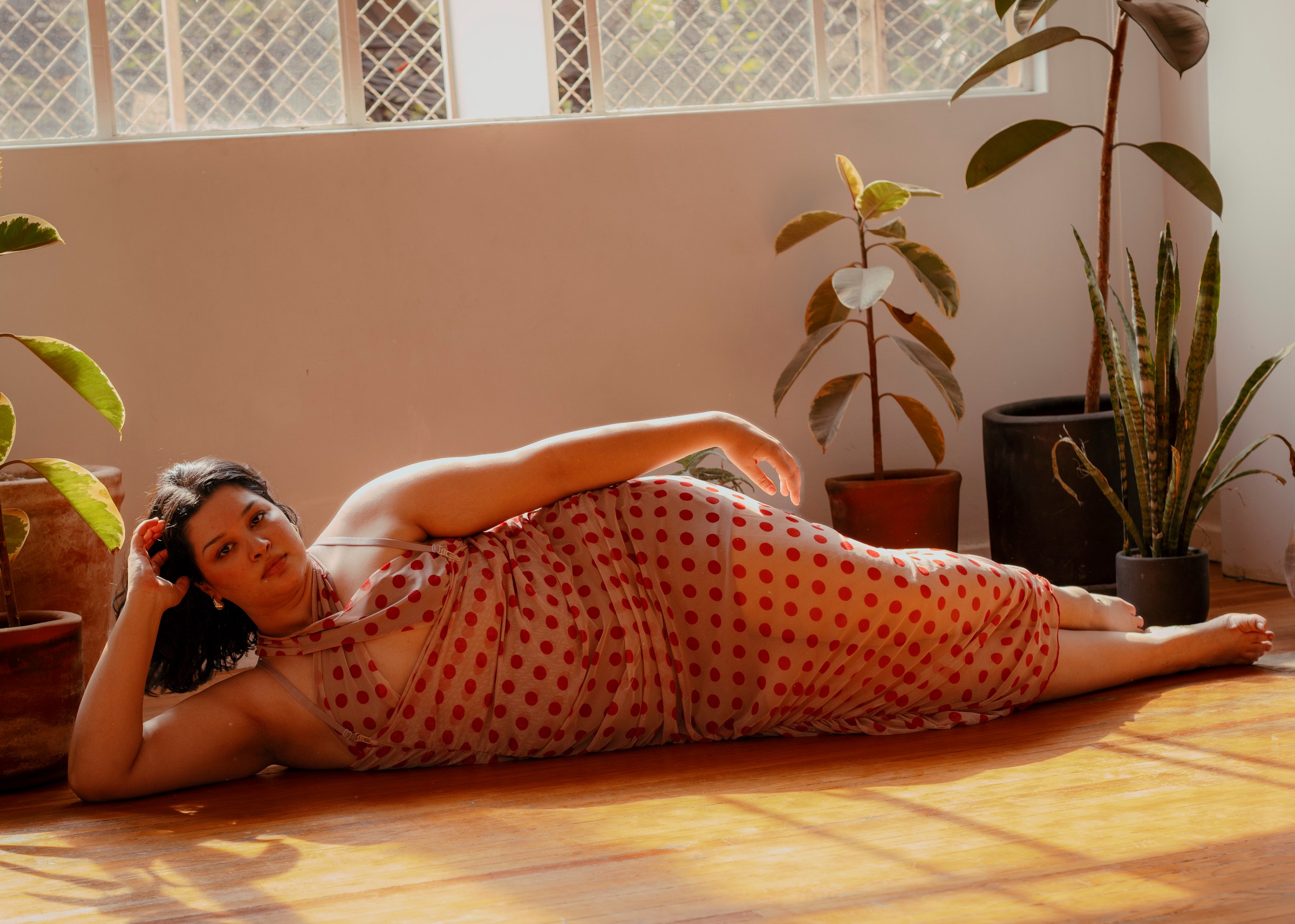 Woman in a red patterned dress standing among houseplants