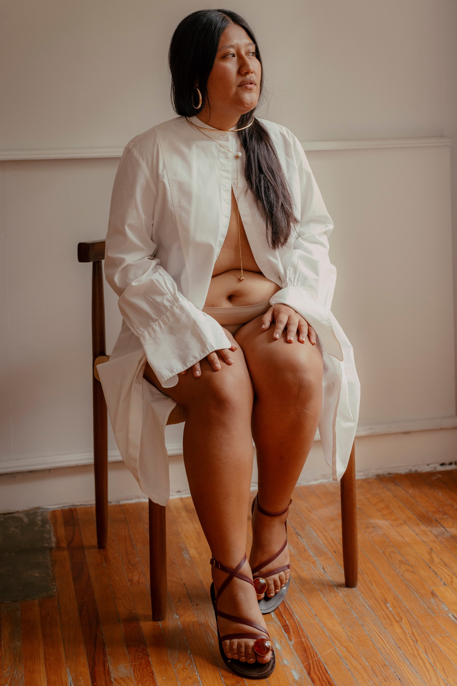 Woman seated in a white shirt looking toward the window
